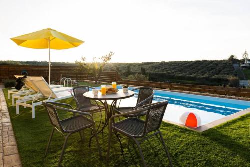 a table with chairs and an umbrella next to a pool at Villa Õtium in Epáno Váthia