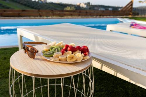 a plate of fruit and vegetables on a table near a pool at Villa Õtium in Epáno Váthia