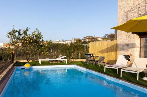 a swimming pool with two chairs and an umbrella at Villa Õtium in Epáno Váthia