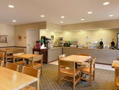 a restaurant with tables and chairs and a kitchen at Super 8 by Wyndham Topeka at Forbes Landing in Topeka