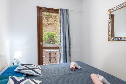 a bedroom with a bed and a window with a chair at il gabbiano castelsardo in Castelsardo