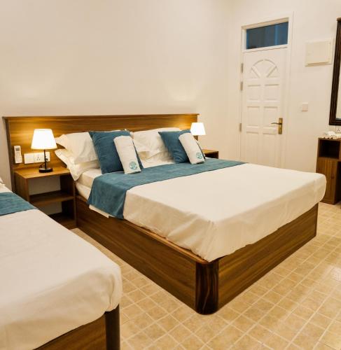 a bedroom with two beds with blue and white pillows at Vaagali Inn in Keyodhoo