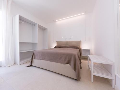 a white bedroom with a bed and a table at Maruzza Home in Favignana