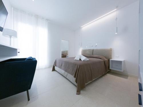 a white bedroom with a bed and a chair at Maruzza Home in Favignana