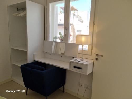 a desk with a blue chair next to a window at Maruzza Home in Favignana