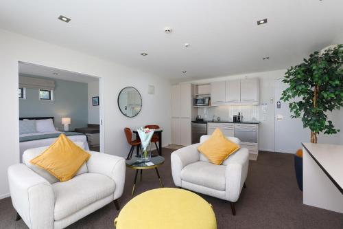 a living room with two chairs and a kitchen at Palazzo Motor Lodge in Nelson