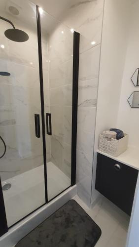 a bathroom with a glass shower with a black rug at LA VALENTINE in Épinal