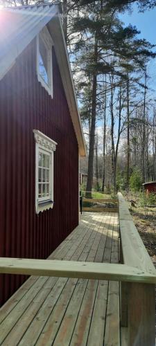 a red building with a wooden deck with a window at Davids Stuga in Klässbol