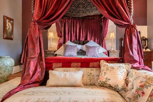 a bedroom with a bed with red curtains and a couch at Calthwaite Hall Bed & Breakfast in Penrith