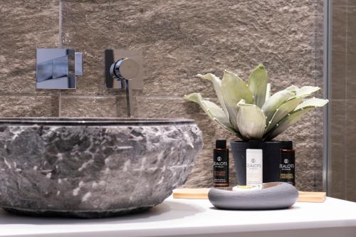 un lavandino in bagno con ciotola e pianta in vaso di VENUS LUXURY APARTMENT a Ermoupoli