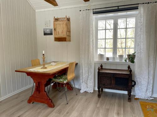 a dining room with a wooden table and a window at Idyllic small farm appartment in Tønsberg