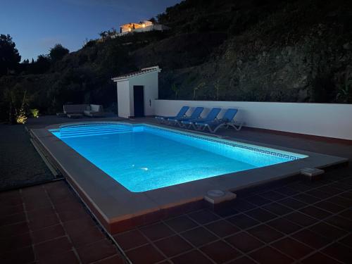 a swimming pool with chairs and a house on a hill at Panoramavilla Lofio Spain in Cómpeta