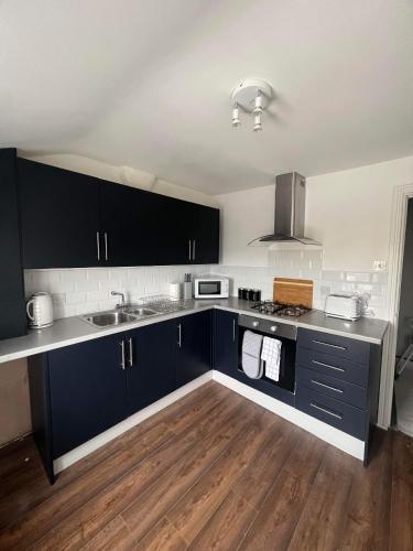 eine Küche mit dunkelblauen Schränken und einem Waschbecken in der Unterkunft Two Bedroom Apartment in Seacombe