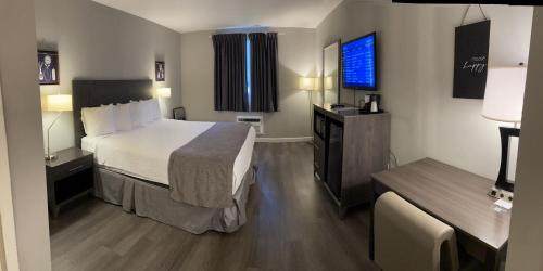 a hotel room with a bed and a television at Carolina Pine Inn near Southern Pines-Pinehurst in Pinebluff