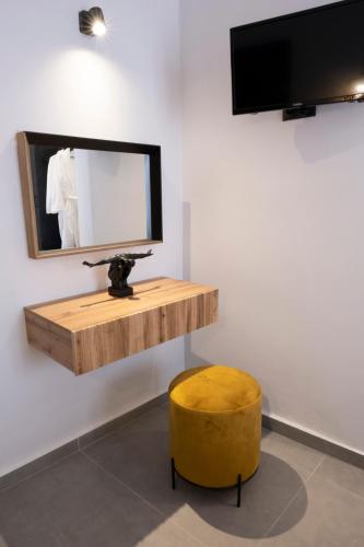 a mirror and a yellow stool in a room at VENUS LUXURY APARTMENT in Ermoupoli