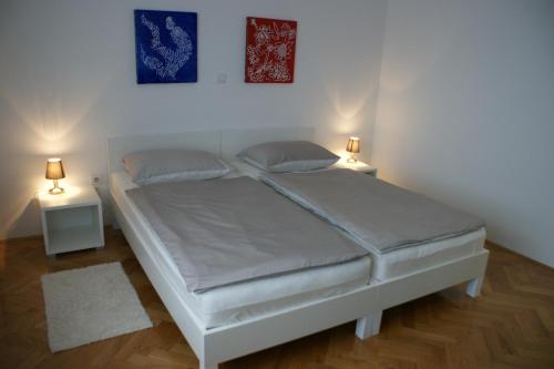 ein weißes Bett in einem Zimmer mit zwei Lampen in der Unterkunft Apartment Majatalo in Zagreb