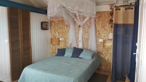 - une chambre avec un lit doté de draps bleus et de rideaux dans l'établissement La cabane du pêcheur, au Gosier