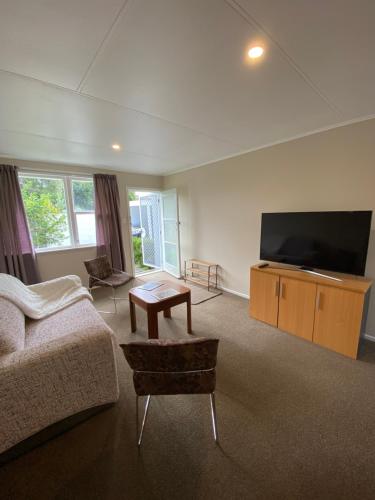 a living room with a couch and a flat screen tv at Birch Court - Harakeke in Whanganui