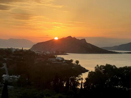 una puesta de sol sobre una montaña y un cuerpo de agua en serenity villa Aegina fantastic view near the beach, en Aegina Town