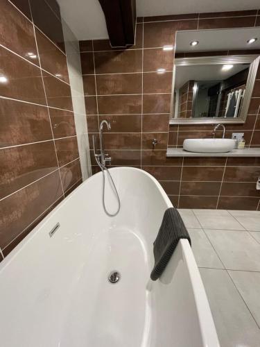 a white bath tub in a bathroom with a mirror at Spacious, luxury town centre Granary conversion in Stamford