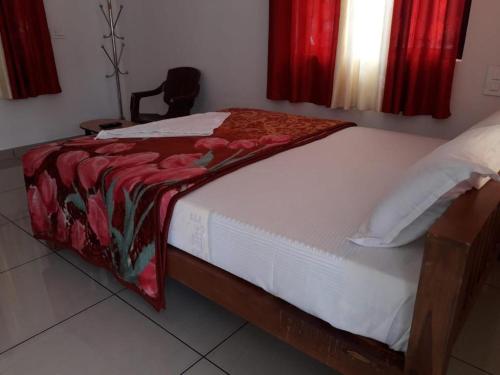 a bedroom with a bed with a red blanket on it at MUNNAR FALCUNS in Anachal