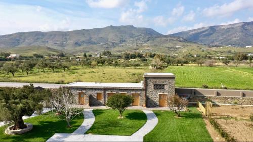 a stone house in a field with mountains in the background at Peristerionas Estate in Karistos