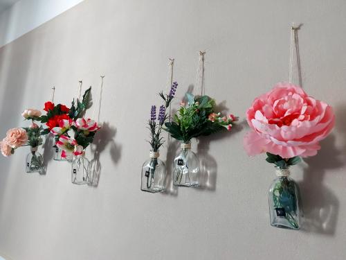 vier glazen vazen met bloemen op een muur bij Grape's Home in Canelli