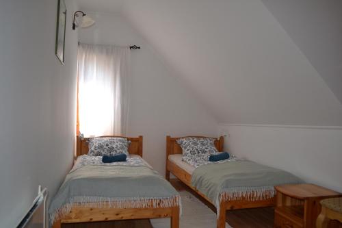 2 camas individuales en una habitación con ventana en Hegyi Füge Vendégház, en Csopak