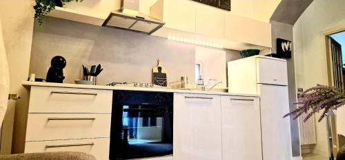 uma cozinha com armários brancos e um forno preto em Le Petit Noah em Pombia