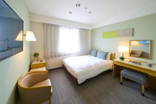 町田市にあるホテルリソル町田のベッドとデスクが備わるホテルルームです。