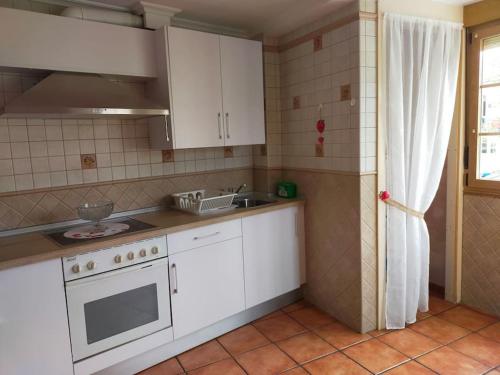 eine Küche mit weißen Schränken, einer Spüle und einem Herd in der Unterkunft Casa Habanerin in figueras