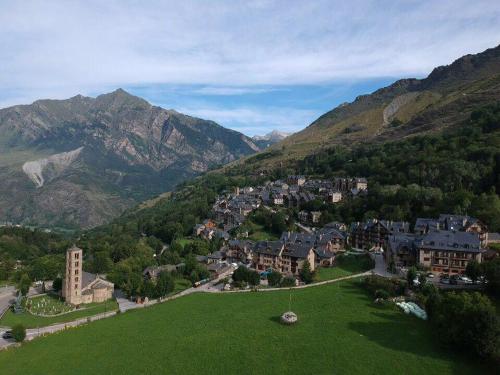 a small town in the mountains with a green field at Apartamento con terraza y vistas panorámicas en Taüll con plaza de parking in Taull