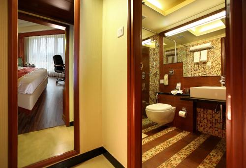 a bathroom with a toilet and a sink and a bed at La Classic- Attibele, Hosur in Attibele