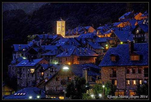 a city at night with a clock tower in a town at Apartamento con terraza y vistas panorámicas en Taüll con plaza de parking in Taull