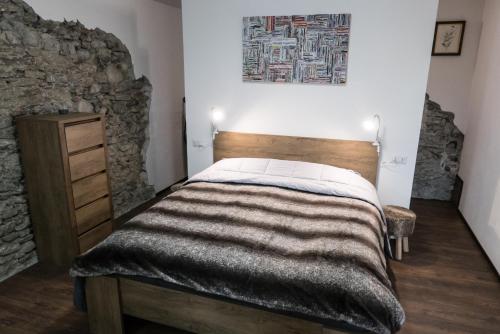 Casa Nenette VDA-AOSTA- n0108 في أَويستا: غرفة نوم بسرير وجدار حجري