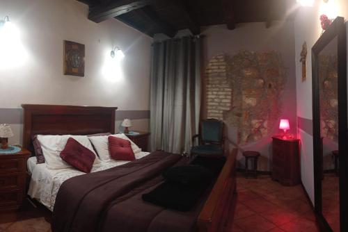 een slaapkamer met een bed met rode kussens en een stoel bij Casa Appartamento per Vacanze - CASA CAMPANFIORE - Al Centro Storico di ZAGAROLO in Zagarolo