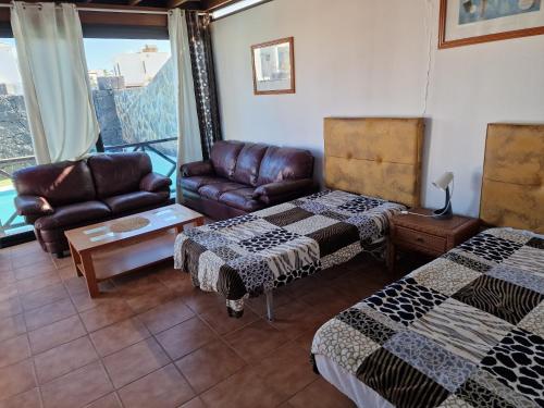un soggiorno con 2 letti e un divano di villa martha a Yaiza