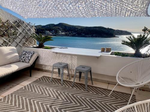 a balcony with a table and stools and a view of the ocean at Front de mer 35m2 vue époustouflante in Carry-le-Rouet