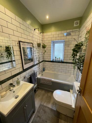 a bathroom with a tub and a sink and a toilet at Apple Street Cottage in Oxenhope
