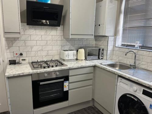 a kitchen with a stove top oven next to a sink at A beautiful ground-floor flat. in London