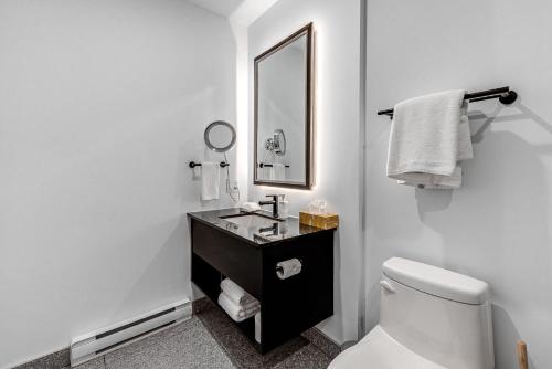 Baño blanco con aseo y espejo en Hébergement touristique ▐ 335 Saint Joseph E▐, en Quebec
