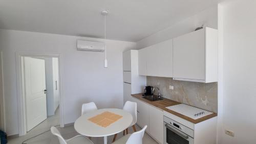 eine weiße Küche mit einem Tisch und weißen Schränken in der Unterkunft Toni Apartment in Sarandë
