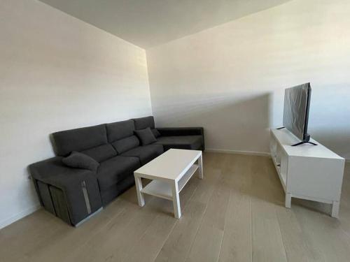 - un salon avec un canapé, une télévision et une table dans l'établissement Apartamento Luda, à Torreperogil