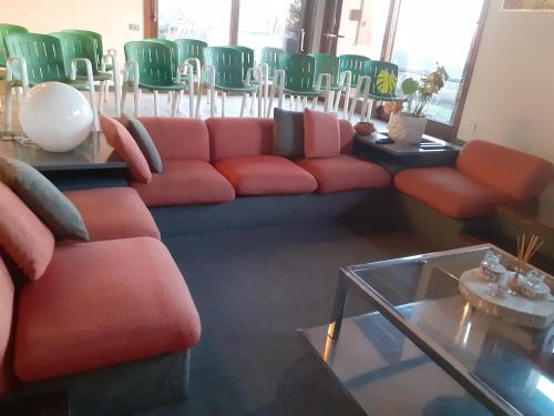 a living room with a red couch and green chairs at Oasi di Mastarone - Il vino e le Rose in Momperone