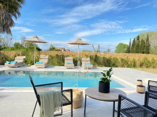 un patio con tavolo, sedie e piscina di My Corfu Luxury Villa with private pool at Sidari a Sidari