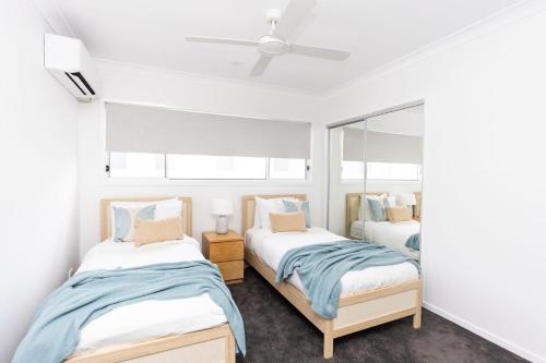 a bedroom with two beds and a mirror at Sea Poppy in Casuarina