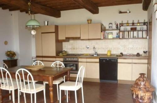 cocina con mesa de madera y sillas blancas en Casa Adrigagi, en Pratolino