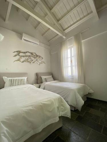a white bedroom with two beds and a window at Spetses Cozy Villa in Spetses