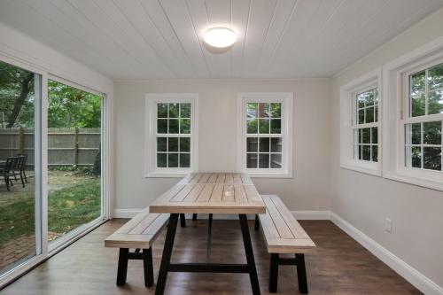 a table and benches in a room with windows at Cape Cod - Dennis Beach House - Walk to the Beach in Dennis