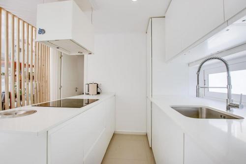 eine Küche mit weißen Arbeitsflächen und einem Waschbecken in der Unterkunft White and Light House in Costa da Caparica
